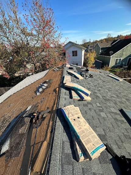 Roof tear-off with new shingle bundles staged on ridge, Portland OR