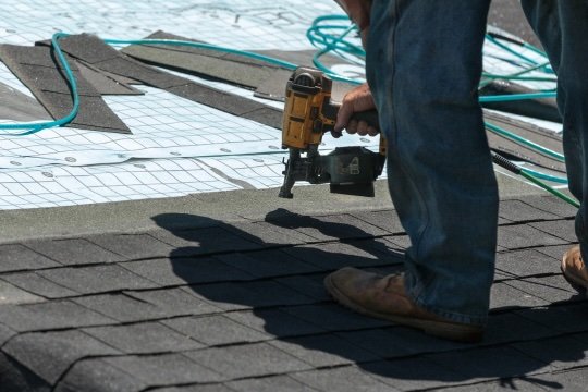 Roofer nailing architectural shingles with nail gun, Portland OR